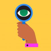 A banner image showing a hand holding a blue magnifying glass with an eye where the lens would normally be.